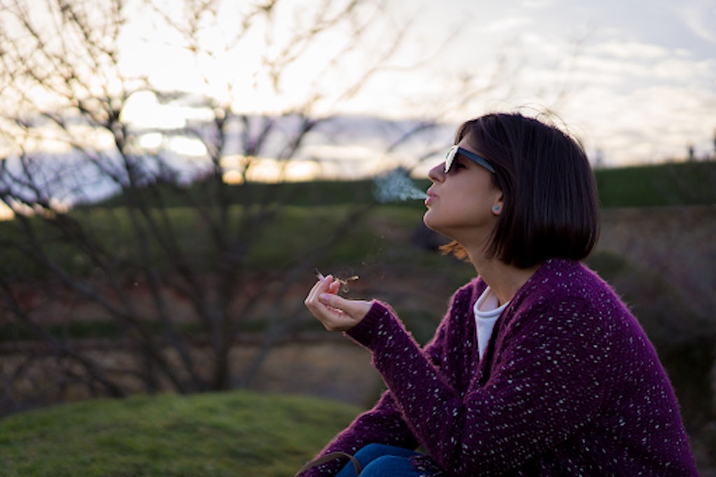 Beautiful female smoking weed in nature