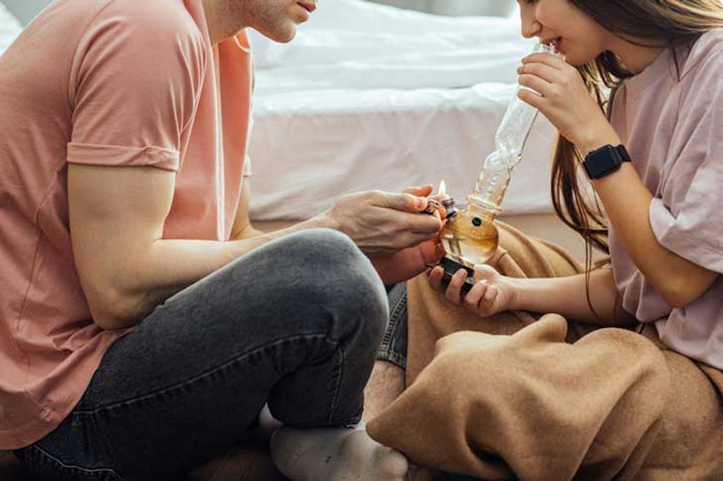 A couple smokes marijuana from a bong