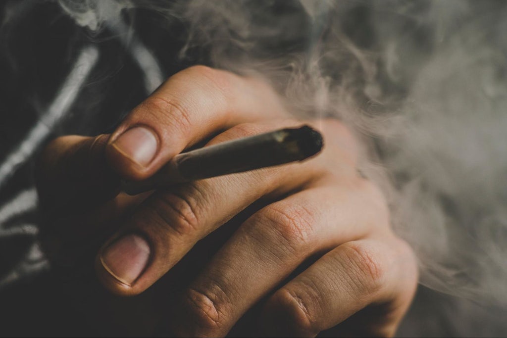 A man smokes, a joint and a lighter in his hands