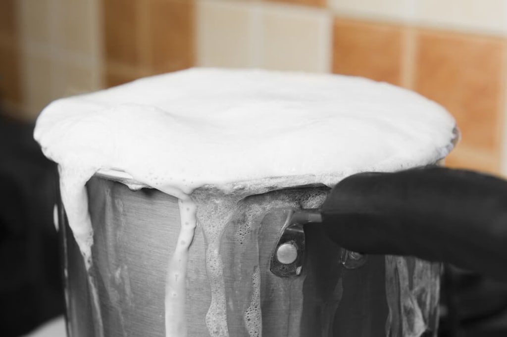 milk boiling over in a pot on the stove
