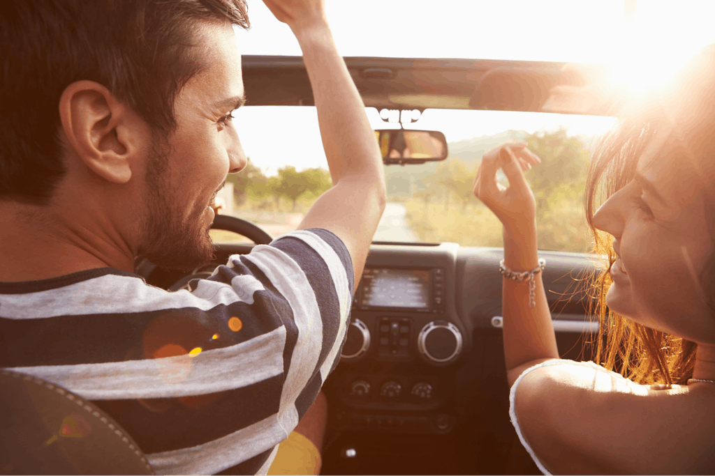 A young couple driving along a country road